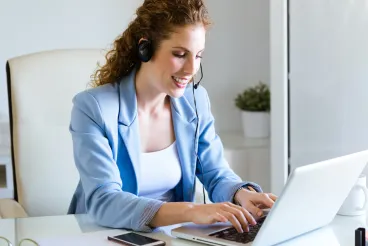 Une dame avec un casque à son bureau pour illustrer la conciergerie d'entreprise