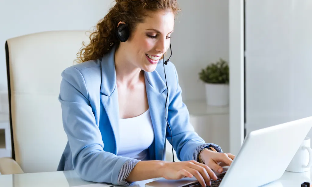 Une dame avec un casque à son bureau pour illustrer la conciergerie d'entreprise